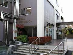 白い外壁の建物を正面階段側から。入口上部に館名サインあり